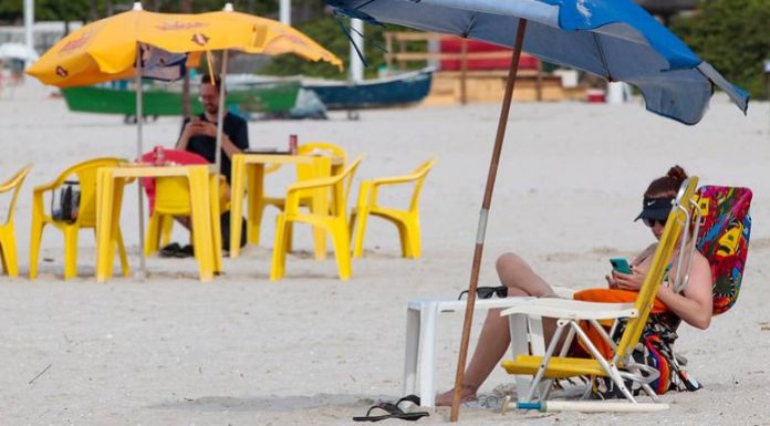pessoas sentadas em cadeiras na praia - itapema proíbe caixas de som na praia