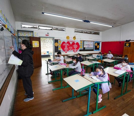Proposta de revisão de salários da educação estadual desagrada servidores professora em sala de aula com alunos afastados e todos de máscara - descompactaçaõ da tabela do magistério em pauta em santa catarina