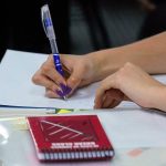 prova de acts em sc adiada para dezembro -close em braços de mulher escrevendo em caderno sobre carteira