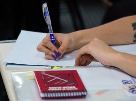 prova de acts em sc adiada para dezembro -close em braços de mulher escrevendo em caderno sobre carteira