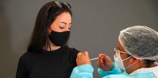 moça olha para enfermeira aplicando vacina em seu braço; Remessa de vacinas para adolescentes chega a SC na quinta-feira