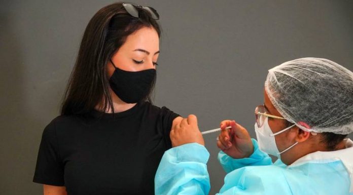 moça olha para enfermeira aplicando vacina em seu braço; Remessa de vacinas para adolescentes chega a SC na quinta-feira