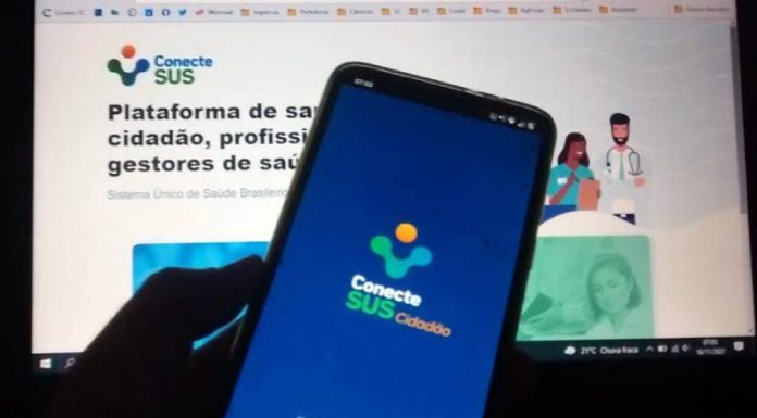 celular com aplicativo conectesus utilizado para comprovante de vacinação em frente a tela de computado com site do conectesus