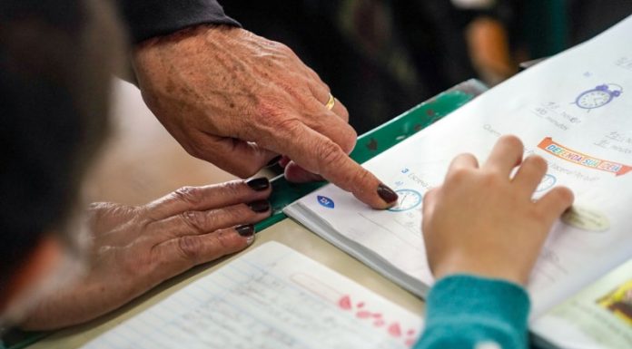 close em mão de professora apontando algo em livro para aluna - magistério estadual professores do estado reajuste salarial profisssionais de educação