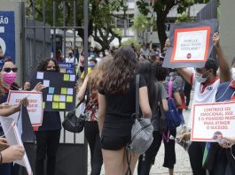 estudantes entrando em local de provam com pessoas no portão segurando cartazes e de máscara - Segundo dia do Enem tem provas de matemática e ciência da natureza