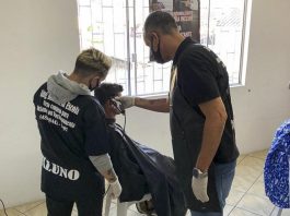 dois homens cortam cabelo de homem em cadeira de barbeiro - Do corte de cabelo à desintoxicação, Centro POP de São José atua na reconstrução de vidas