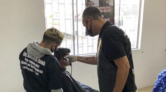 dois homens cortam cabelo de homem em cadeira de barbeiro - Do corte de cabelo à desintoxicação, Centro POP de São José atua na reconstrução de vidas