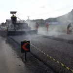 máquina e homens em trabalho de asfaltamento na br-280 - SC começa a aplicar dinheiro estadual em rodovias federais