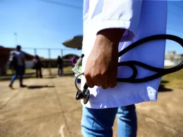 close em mão de profisional de medicina segurando estetoscópio - contração de médicos para reforço do sc