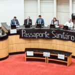 bancada da alesc dos deputados antivacinas com faixa à frente inscrita "passaporte sanitário não"