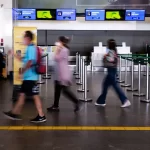 turistas com máscara em saguão de aeroporto