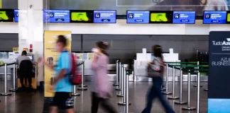 turistas com máscara em saguão de aeroporto