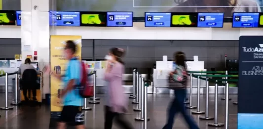 turistas com máscara em saguão de aeroporto