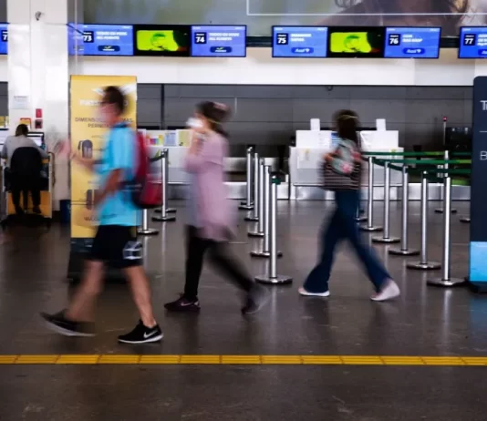 turistas com máscara em saguão de aeroporto