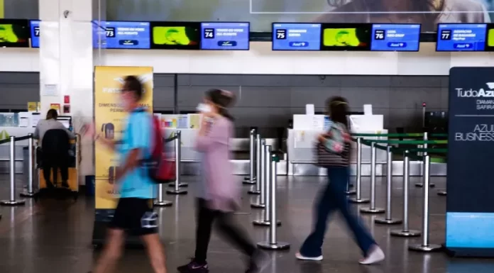 turistas com máscara em saguão de aeroporto