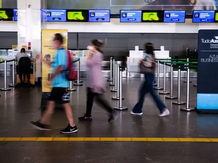 turistas com máscara em saguão de aeroporto