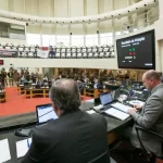 deputados na mesa da presidência da alesc com bancadas e demais parlamentares em baixo ao fundo