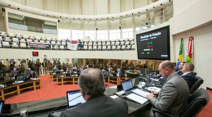 deputados na mesa da presidência da alesc com bancadas e demais parlamentares em baixo ao fundo