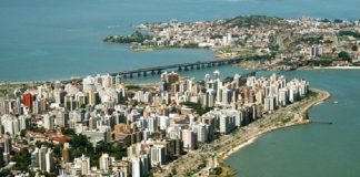 foto aérea de florianópolis, com prédios e orla da beira-mar em primero plano, pontes e região do continente