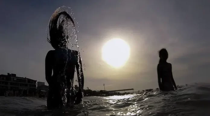 banho de mar em sc - silhueta de duas pessoas na água - relatório de balneabilidade