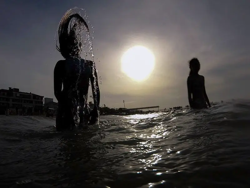 banho de mar em sc - silhueta de duas pessoas na água - relatório de balneabilidade