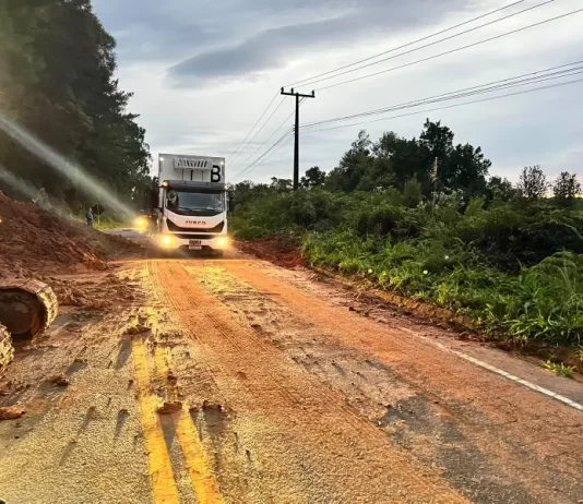 caminhão passando por parte da pista da sc-108 ao lado de queda de barreira