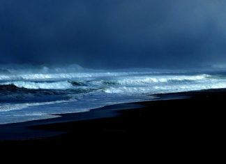 foto de uma praia no início da noite com mar agitado, ventos fortes e muitas nuvens - previsão do tempo de chuva em sc