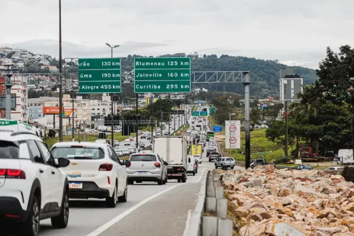 Vista da Via Expressa com tráfego de veículos; ao lado, a via marginal exibe pedras instaladas para impedir ocupações irregulares.