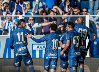 Da Ressacada ao Natal: reflexões sobre crise, excessos e a espera por dias melhores Cinco jogadores do Avaí aparecem em primeiro plano, usando o uniforme oficial azul do time. Estão no gramado da Ressacada, comemorando intensamente a vitória por 2 a 0 sobre o Cuiabá. Alguns se abraçam, outros erguem os braços em sinal de comemoração. Ao fundo, a arquibancada está cheia de torcedores vibrando, muitos em pé, celebrando a conquista com entusiasmo.