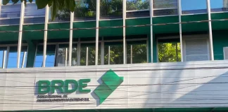 Fachada moderna do prédio do BRDE, com paredes de vidro e logotipo em destaque na entrada
