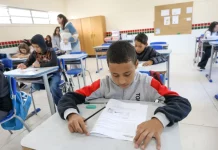 Alunos participam de avaliação em sala de aula no programa Educação Levada a Sério, enquanto a professora circula acompanhando o desempenho.