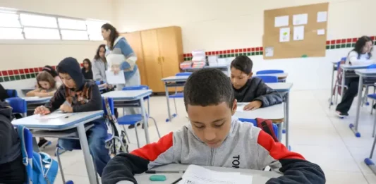Alunos participam de avaliação em sala de aula no programa Educação Levada a Sério, enquanto a professora circula acompanhando o desempenho.