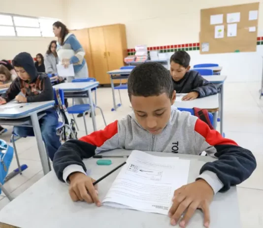 Alunos participam de avaliação em sala de aula no programa Educação Levada a Sério, enquanto a professora circula acompanhando o desempenho.