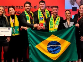 Representantes da Next Shipping posam segurando a bandeira do Brasil e exibindo medalhas e o certificado recebidos durante a cerimônia de premiação do ranking Great Place To Work 2025, em reconhecimento à excelência na gestão de pessoas.