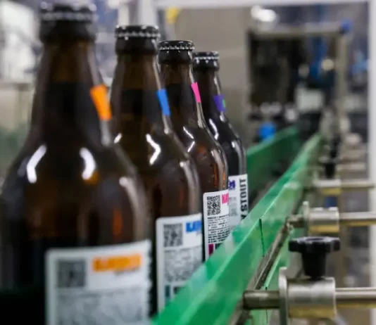 Linha de engarrafamento em cervejaria moderna, ilustrando o crescimento e a liderança de Santa Catarina na abertura de novas cervejarias.