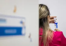 Imagem de enfermeira preparando uma seringa com a vacina contra a Influenza, em um ambiente de saúde, durante a vacinação dos grupos prioritários.