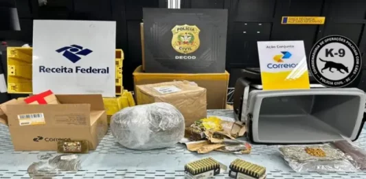 Na foto, aparecem os emblemas da Receita Federal, da Polícia Civil e dos Correios alinhados na parte superior. Abaixo, sobre uma superfície clara, estão expostas armas, munições e substâncias entorpecentes apreendidas na operação que investigou encomendas enviadas pelos Correios.