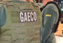 Foto mostra dois policiais do Gaeco de costas, ambos usando coletes à prova de balas.