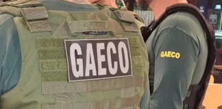 Foto mostra dois policiais do Gaeco de costas, ambos usando coletes à prova de balas.