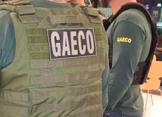 Foto mostra dois policiais do Gaeco de costas, ambos usando coletes à prova de balas.