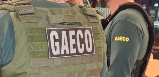 Sistema de pagamentos da Prefeitura de São José é invadido por hackers Foto mostra dois policiais do Gaeco de costas, ambos usando coletes à prova de balas.