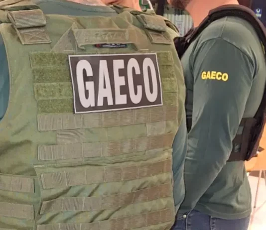 Foto mostra dois policiais do Gaeco de costas, ambos usando coletes à prova de balas.