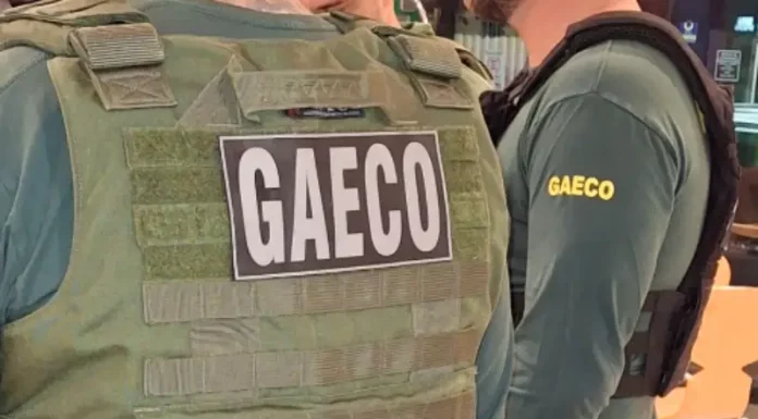 Foto mostra dois policiais do Gaeco de costas, ambos usando coletes à prova de balas.
