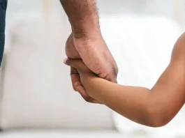 Homem segurando a mão de uma menina, representando famílias que podem solicitar isenção de IPTU em Florianópolis.