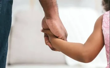 Homem segurando a mão de uma menina, representando famílias que podem solicitar isenção de IPTU em Florianópolis.