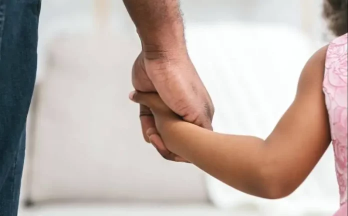 Homem segurando a mão de uma menina, representando famílias que podem solicitar isenção de IPTU em Florianópolis.