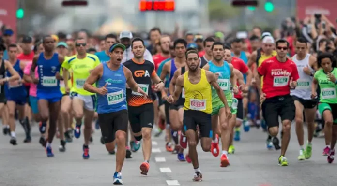 Atletas competindo na Maratona Internacional de Floripa, correndo pelo trajeto nas ruas de Florianópolis, durante as provas de 21km e 42km