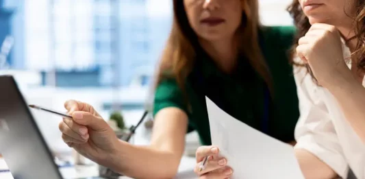 Especialista orienta sobre acertos que podem levar ao sucesso de novos negócios Empresárias analisando planilhas financeiras em laptop, planejando decisões estratégicas para o sucesso de novos negócios