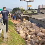 São José dá início a obras para impedir ocupações irregulares Homem de camiseta azul caminhando na marginal da Via Expressa, ao lado de pedras pontiagudas colocadas pela prefeitura para evitar ocupações irregulares.