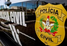 Porta do carro da Polícia Civil da Delegacia de Tijucas, com o logo da instituição visível.